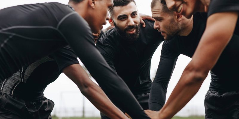 Soccer players joining hands in huddle talking about the game strategy. Low angle view of footballers bending forward in a huddle holding hands.