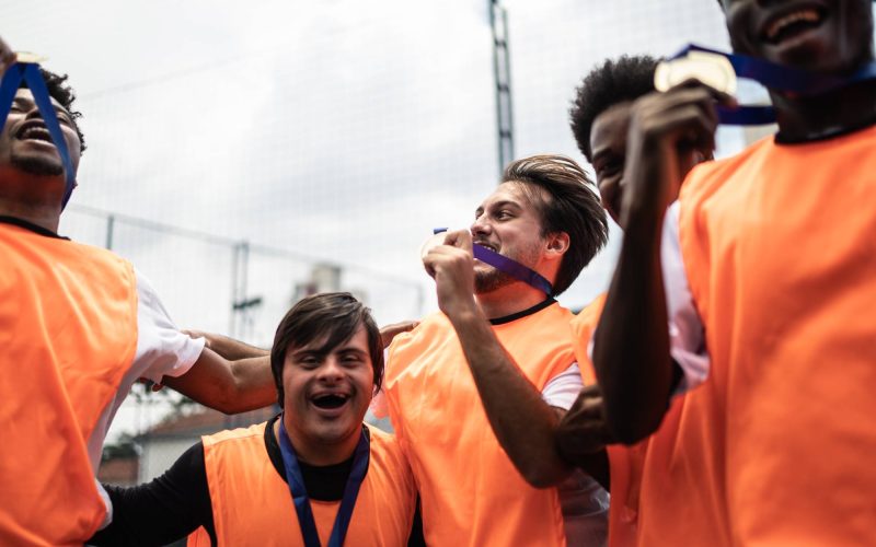Players celebrating winning a medal on the soccer field - including a person with special needs